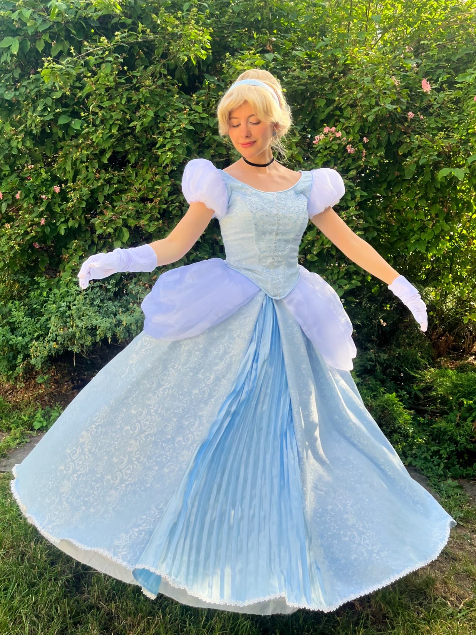 Animatrice déguisée en Cendrillon, robe de bal bleue, tourbillonnant dans un jardin verdoyant, lors d'une animation d'anniversaire Ma Vie de Rêves