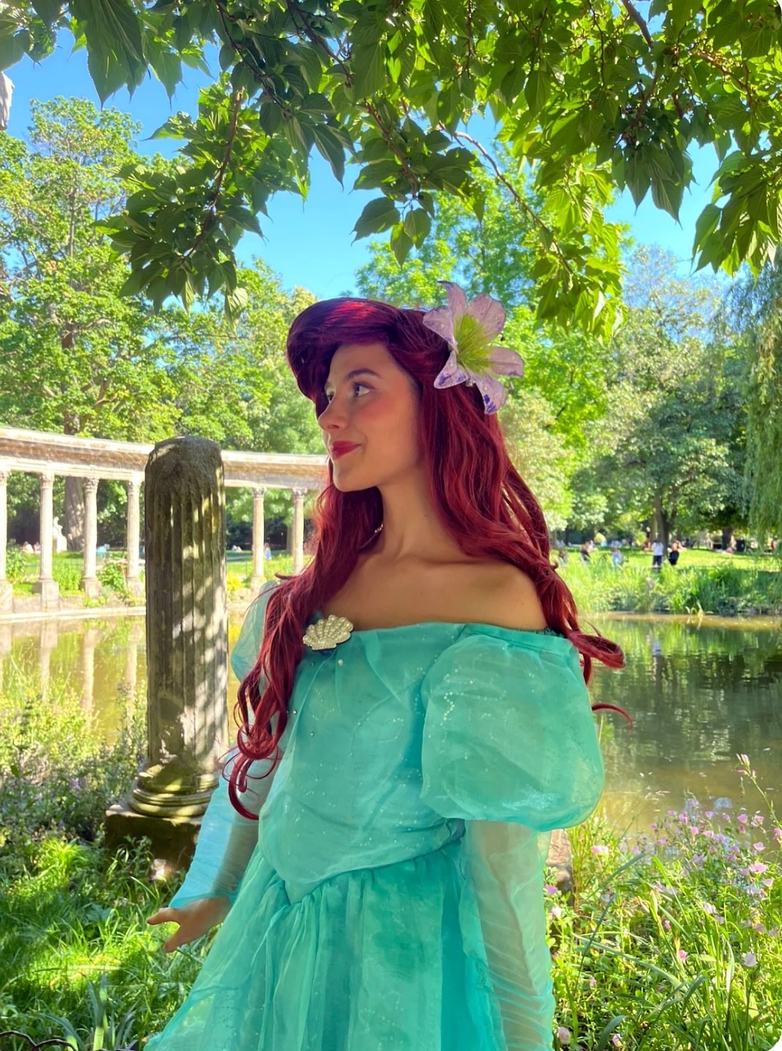 Animatrice costumée en princesse Ariel devant un étang, dans un parc