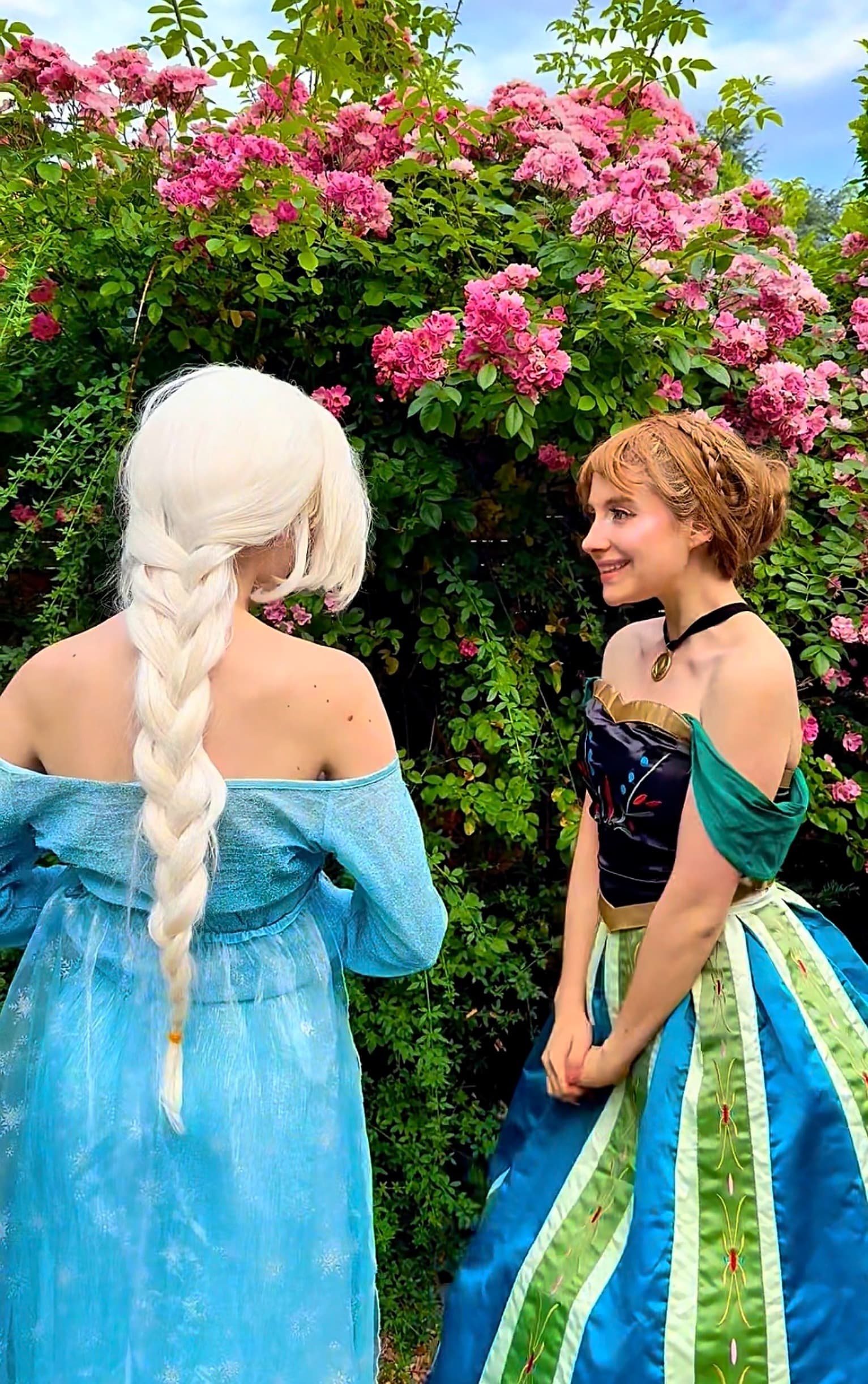 Animatrices costumées en Elsa et Anna devant un massif de roses