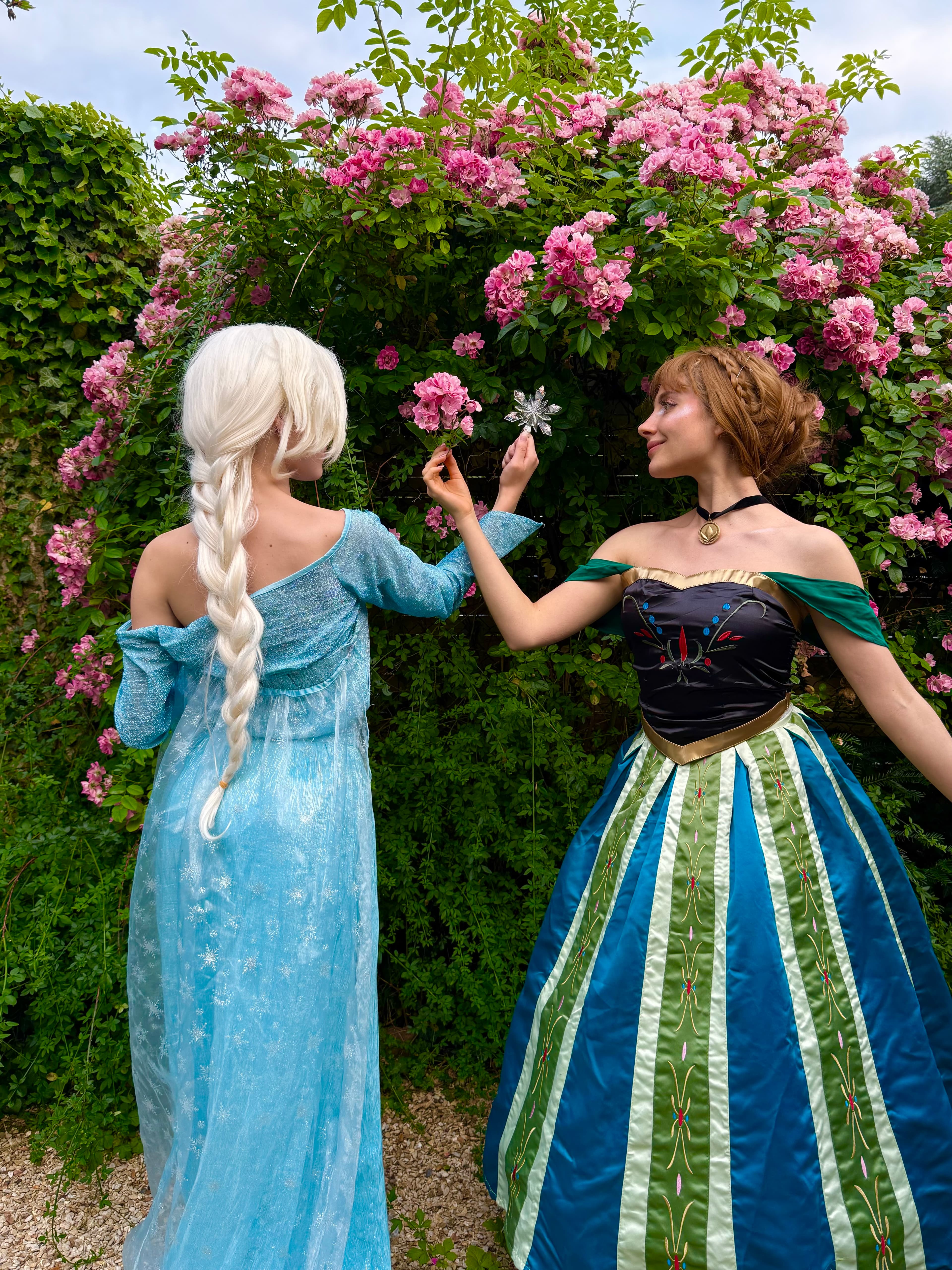 Deux animatrices déguisées en Elsa et Anna (La Reine des Neiges) devant un rosier fleuri, lors d'une animation d'anniversaire Ma Vie de Rêves